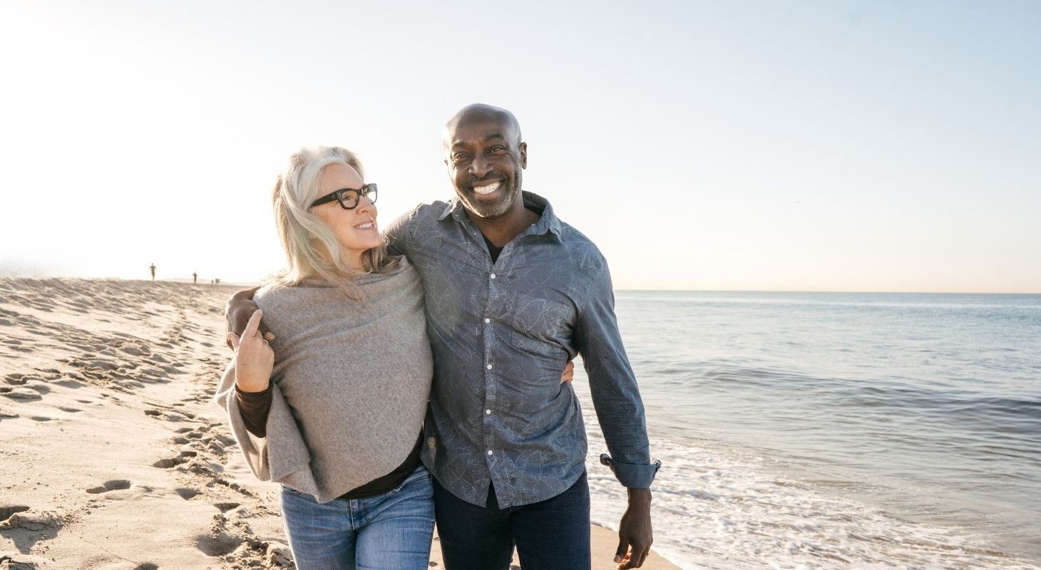 a couple is walking the beach wearing pants and long sleeves