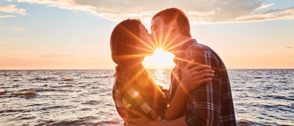 romantic couple kissing by the ocean