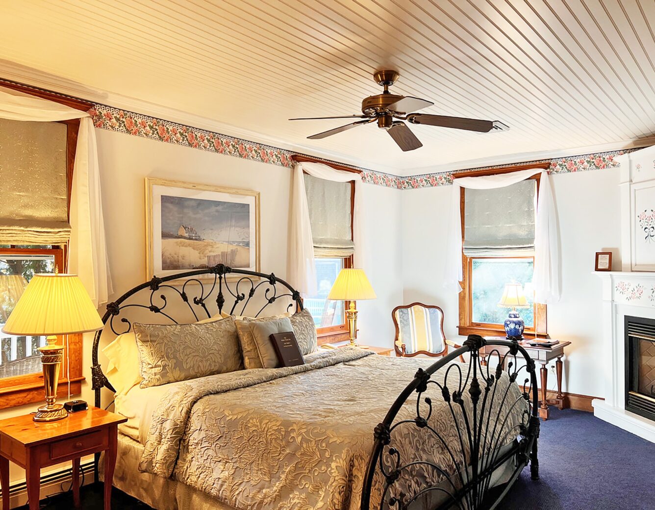 A black iron decorative bed with cream colored bedding, white wooden ceiling and blue carpet