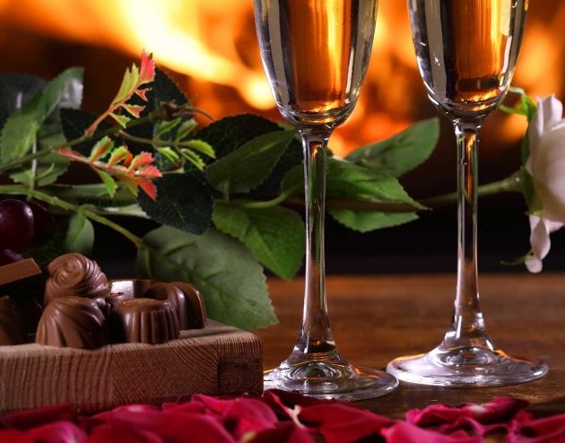 Chocolates, Champagne and roses in front of a fireplace