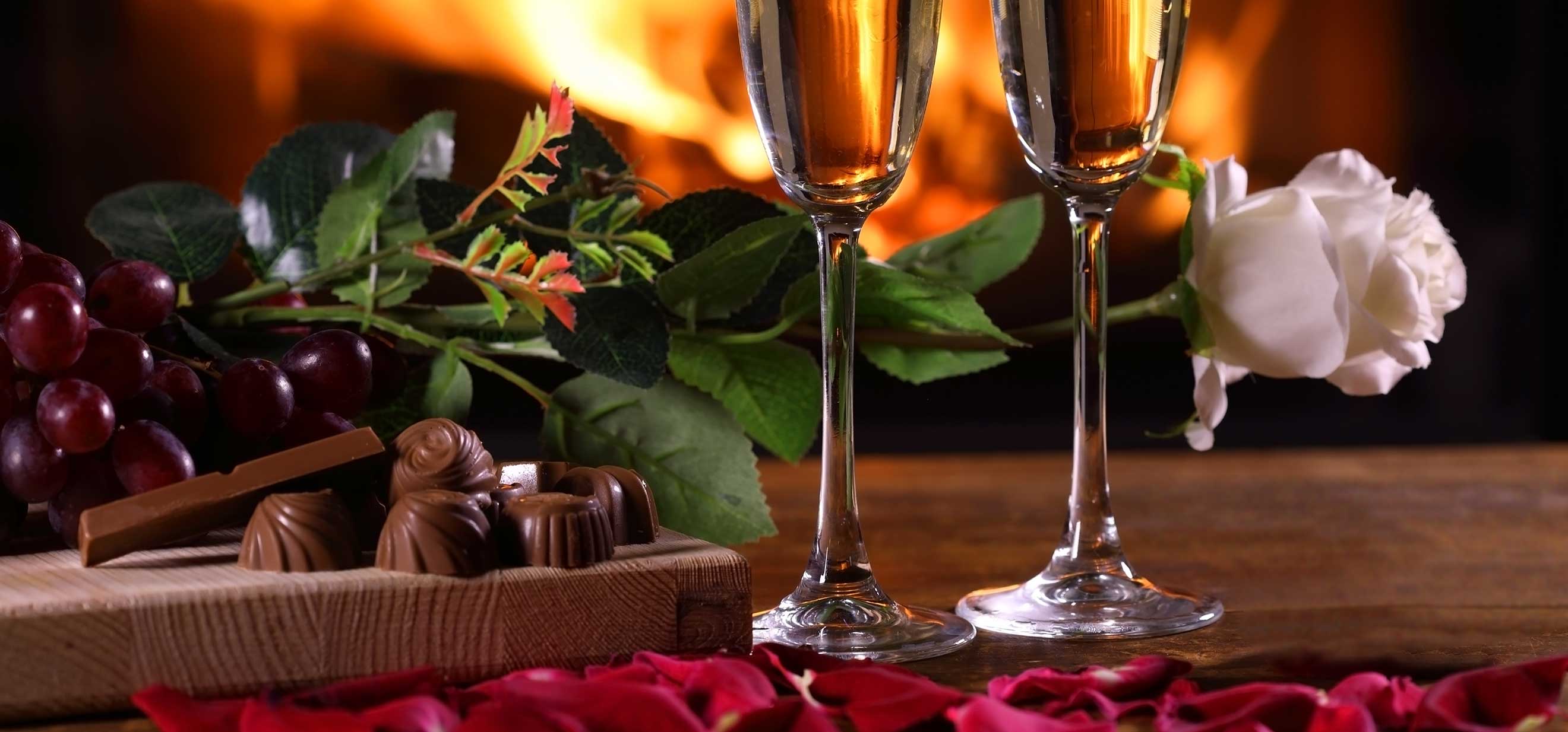 Chocolates, Champagne and roses in front of a fireplace
