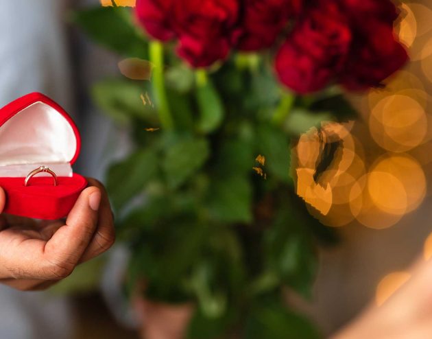 Man proposing with an engagement ring and a dozen red roses