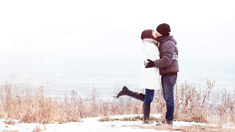 couple kissing by the coast in the winter