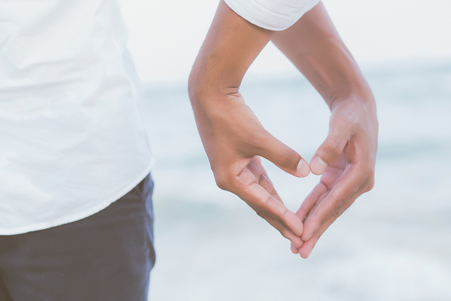 couple's hands making a heart at the beach in Cape Cod