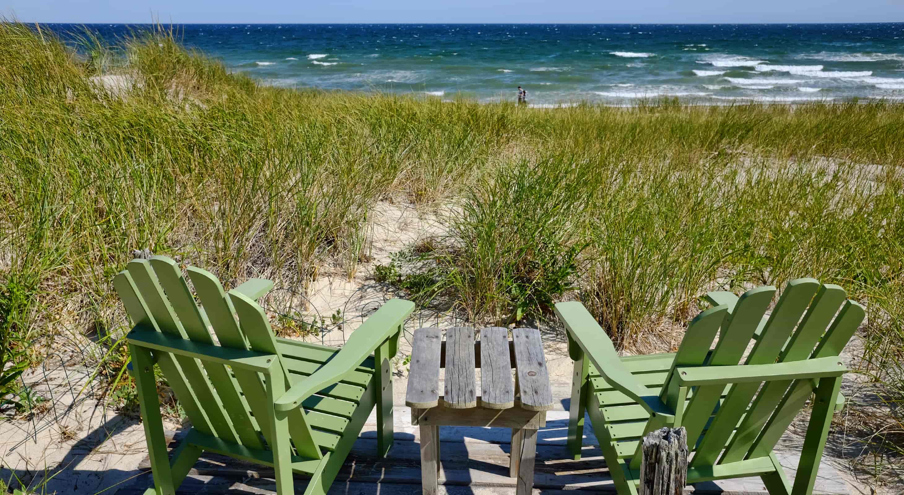Green Adirondack chairs in the sea grass by the ocean