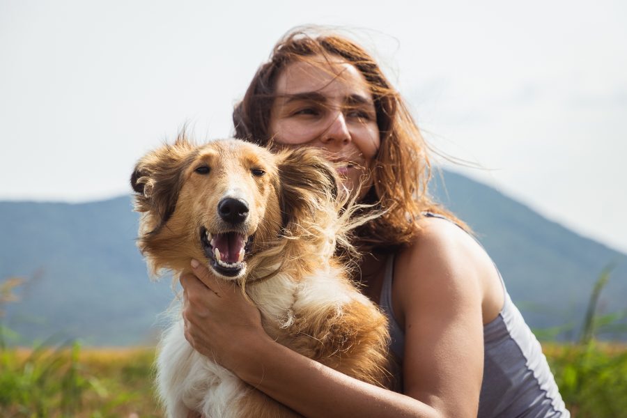 a woman holding a dog in a field