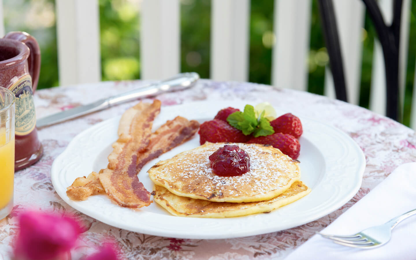 Pancakes with bacon and strawberriesat outside table