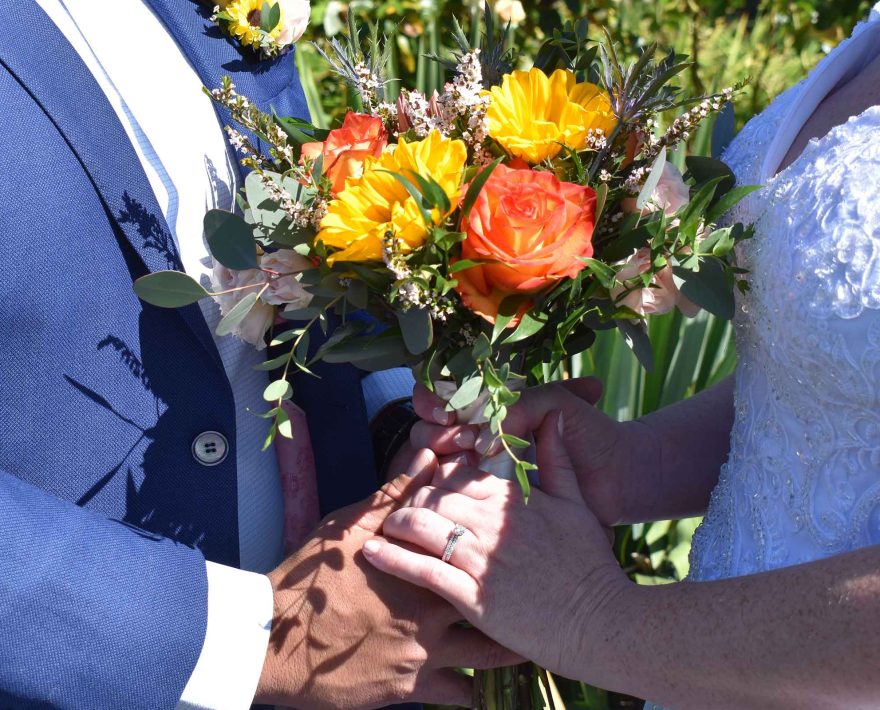 Bride and groom in blue suit with beautiful wedding bouquet