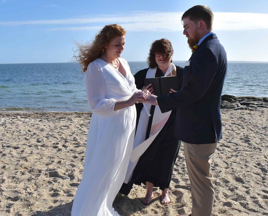 Bride putting ring on groom's finger at Cape Cod elopement on the beach