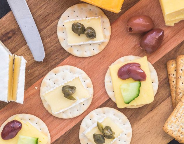 Cutting board with cheese, crackers, olives and fruit