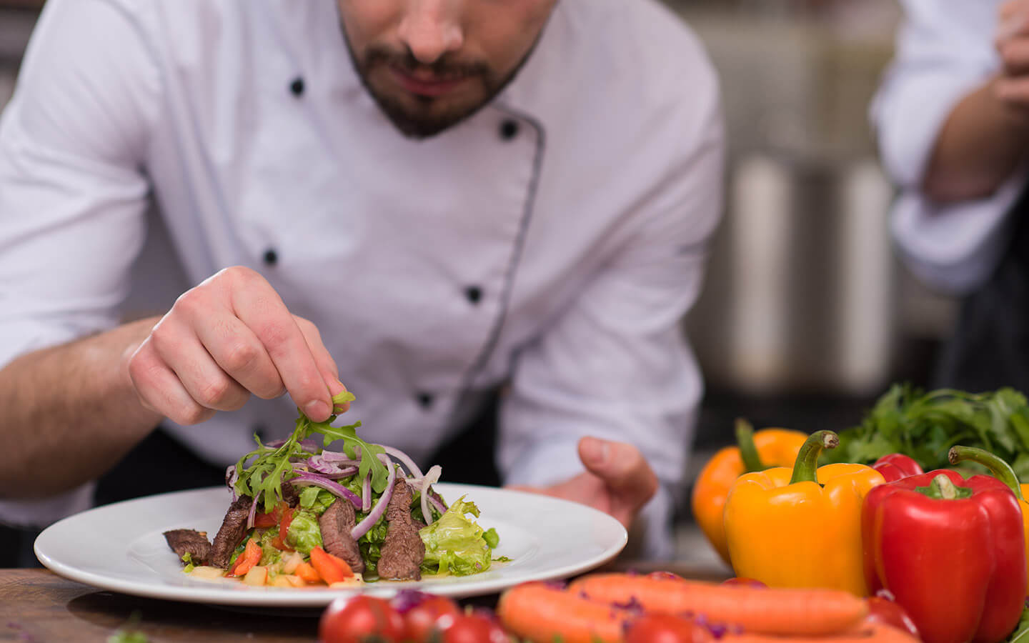 Chef in a white coat preparing a steak salad