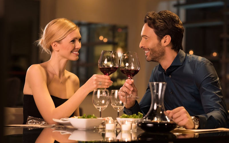 Couple in romantic restaurant with glasses of red wine