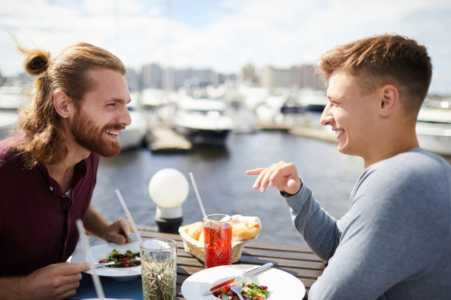 two men having lunch out by a boat dock