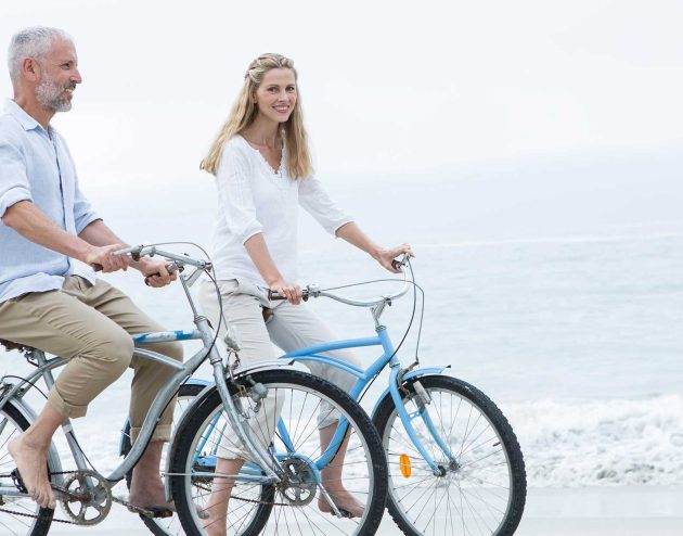 Couple riding bikes on beach