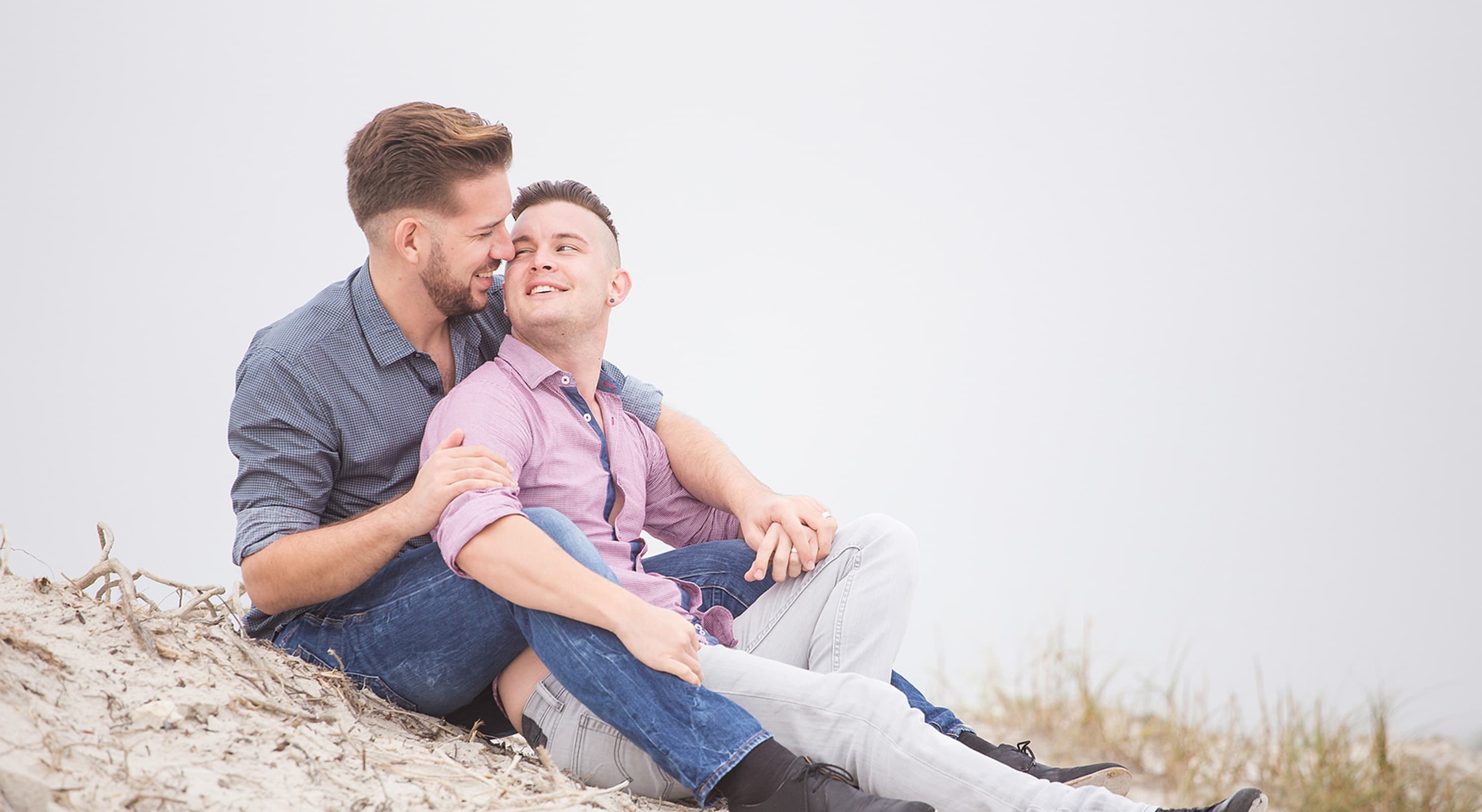 gay couple sitting together at the beach during a Cape Cod getaway