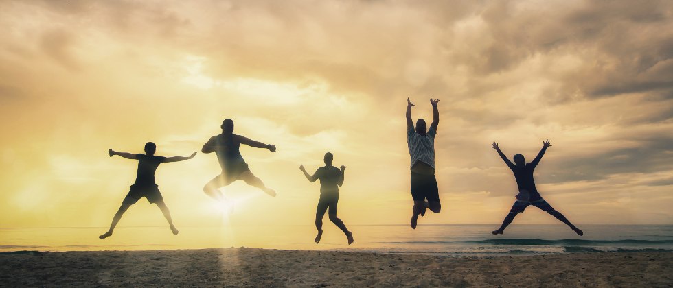 happy group jumping on beach in cape cod