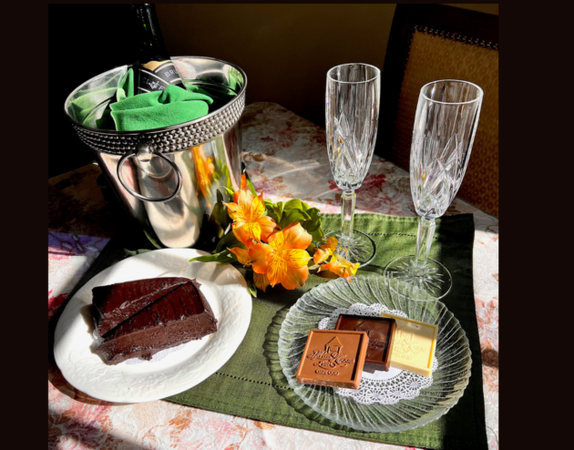 A bottle of champagne on ice, 2 crystal champagne glasses and two places with specialty chocolates