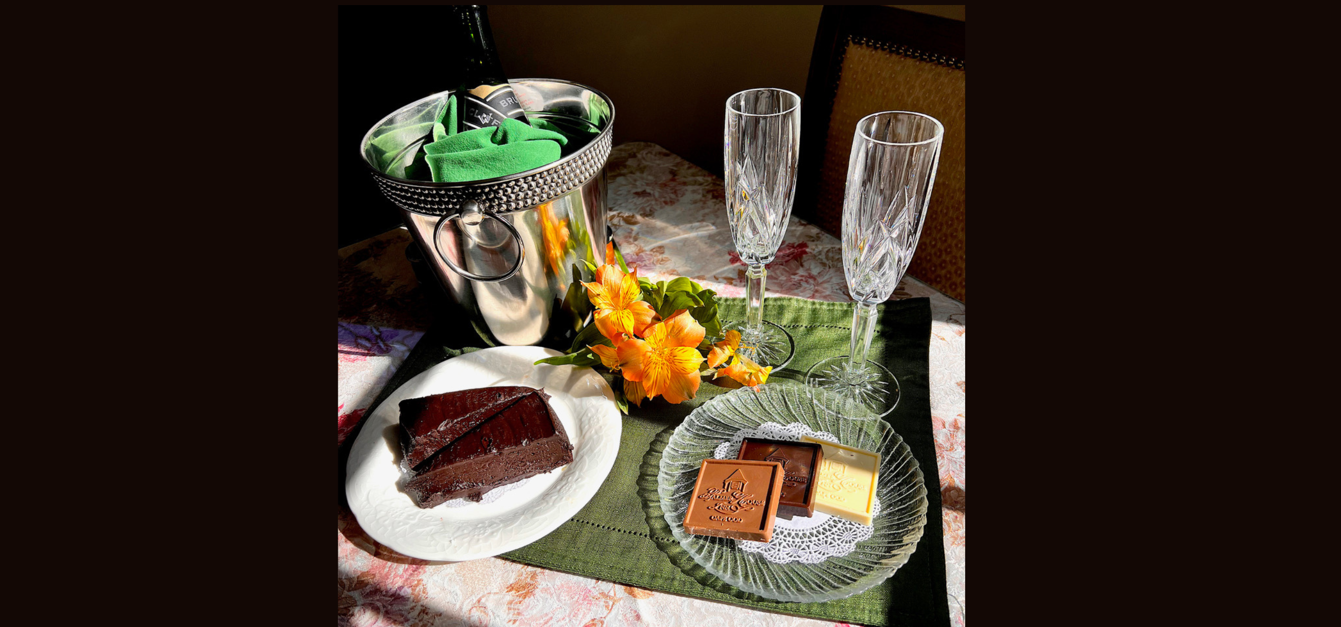 A bottle of champagne on ice, 2 crystal champagne glasses and two places with specialty chocolates