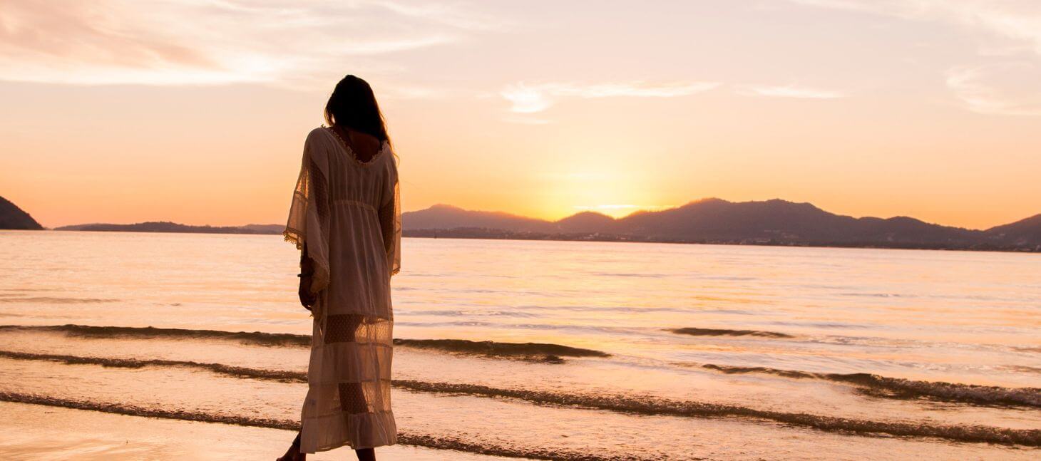 woman walking on beach at sunset