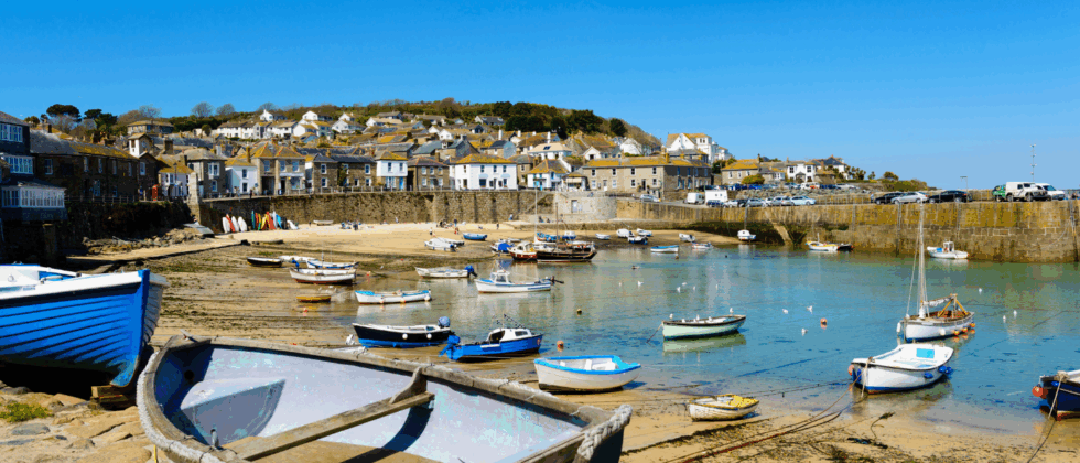 colorful fishing boats resting in a small harbor with stone cottages on a sunny day
