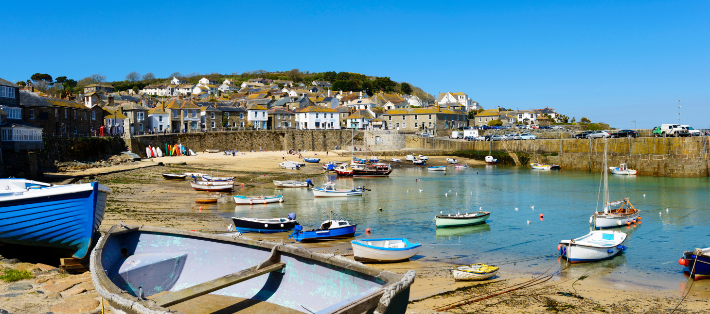 colorful fishing boats resting in a small harbor with stone cottages on a sunny day
